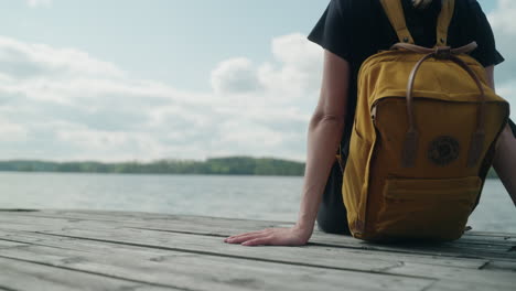 women sits on a pier on a cloudy day, static, close up