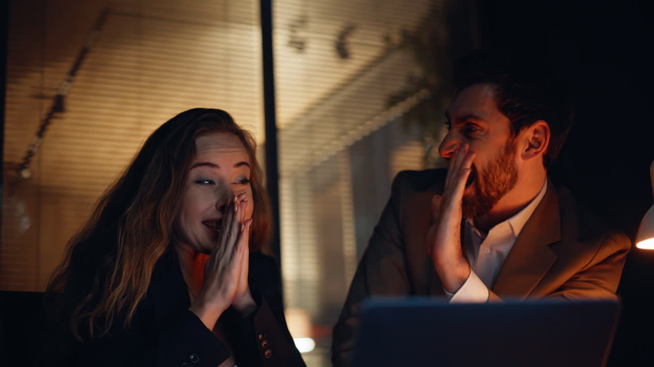 Evening colleagues reading laptop reacting startup win at night office closeup