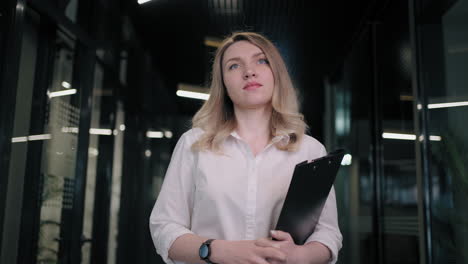 hermosa mujer de negocios caminando en el pasillo de la oficina. mujer de negocios camiñando en una reunión en el interior de la oficina. profesional alegre yendo a la reunión en el corredor del centro de negocios