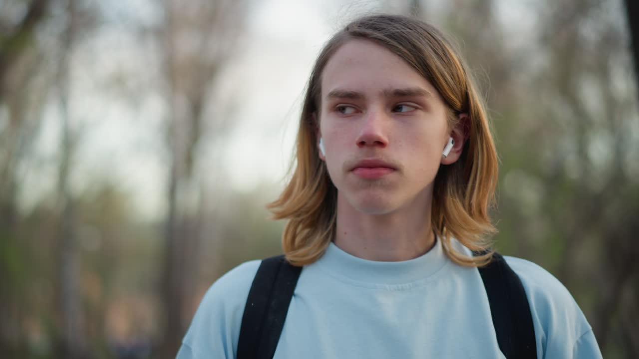 Joven disfrutando de una bebida caliente, adolescente bebiendo café tranquilamente en medio de la luz natural y la vegetación, joven saboreando una bebida humeante al aire libre rodeado de árboles y un suave resplandor matutino
