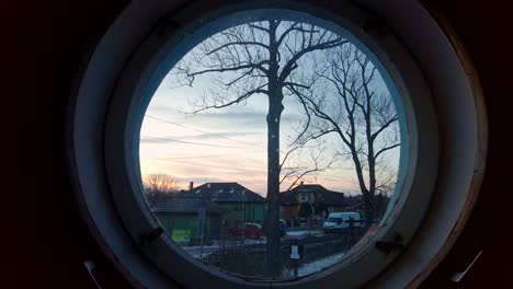 una vista desde una ventana redonda al atardecer en el campo es una escena impresionante que encarna la belleza y la serenidad de la vida rural