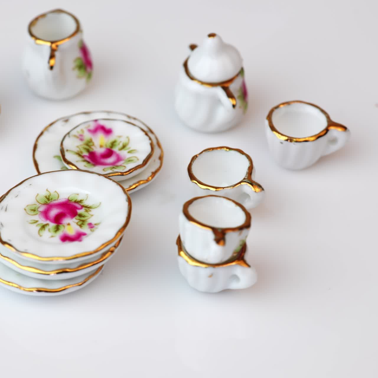 Rotating crockery with bright colorful flowers. Beautiful miniature dishes at white background. Close up