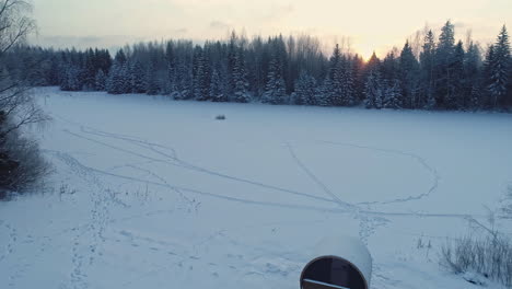 Luftdrohne-Rückwärts-Bewegender-Schuss-über-Holzhütte-Und-Fasssauna-Auf-Einer-Weißen-Schneebedeckten-Landschaft-Während-Der-Morgenzeit