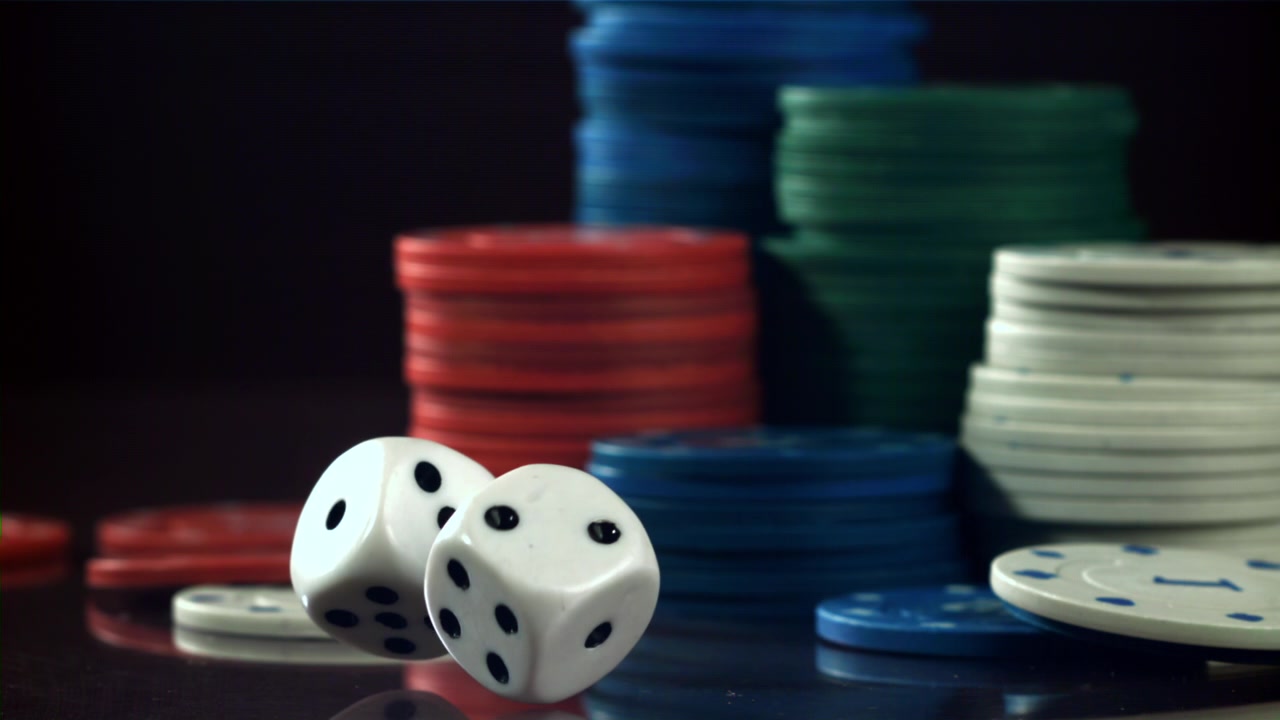 Due dadi bianchi che cadono e si posano vicino a pile di fiches da poker