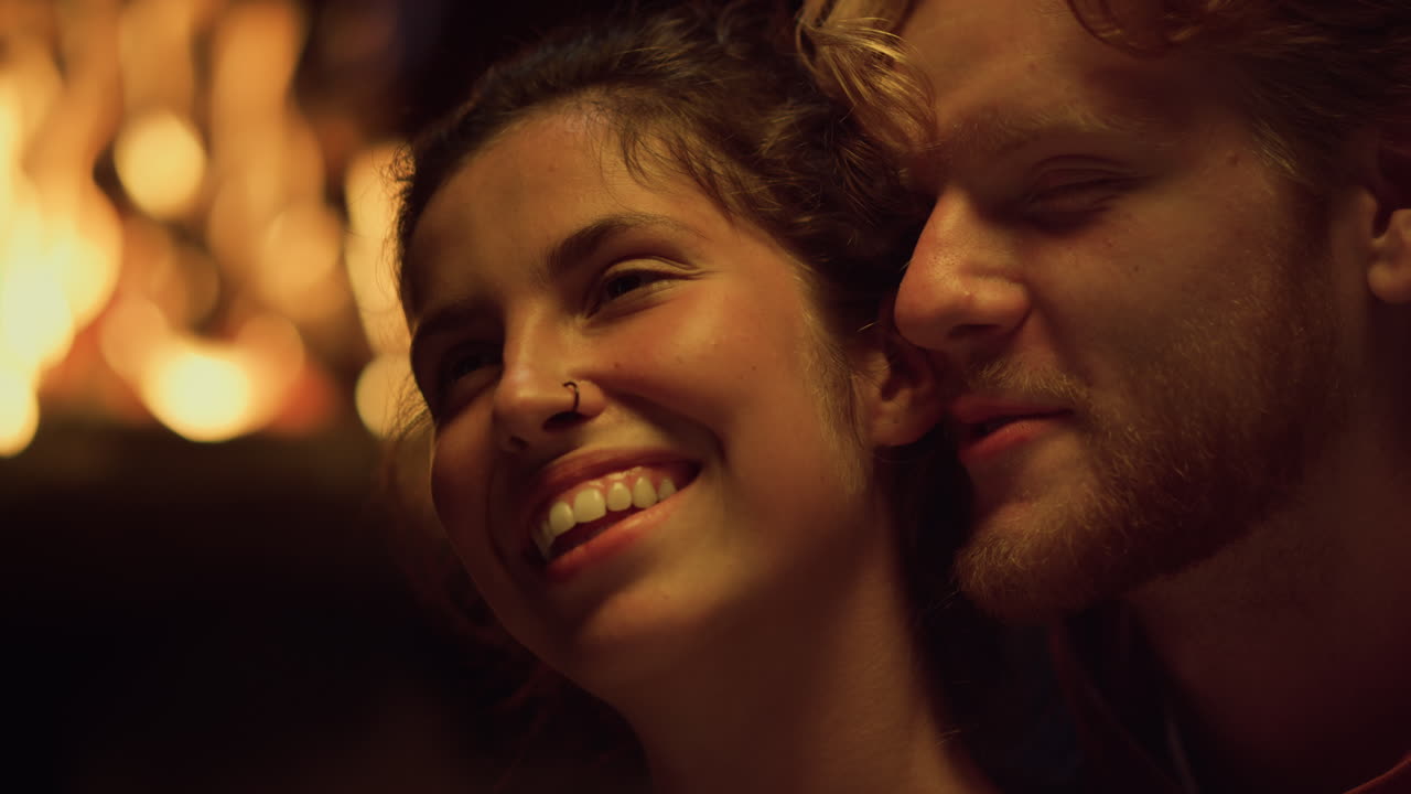 Closeup couple faces flirt at romantic date. Two lovers enjoy relax by fireplace