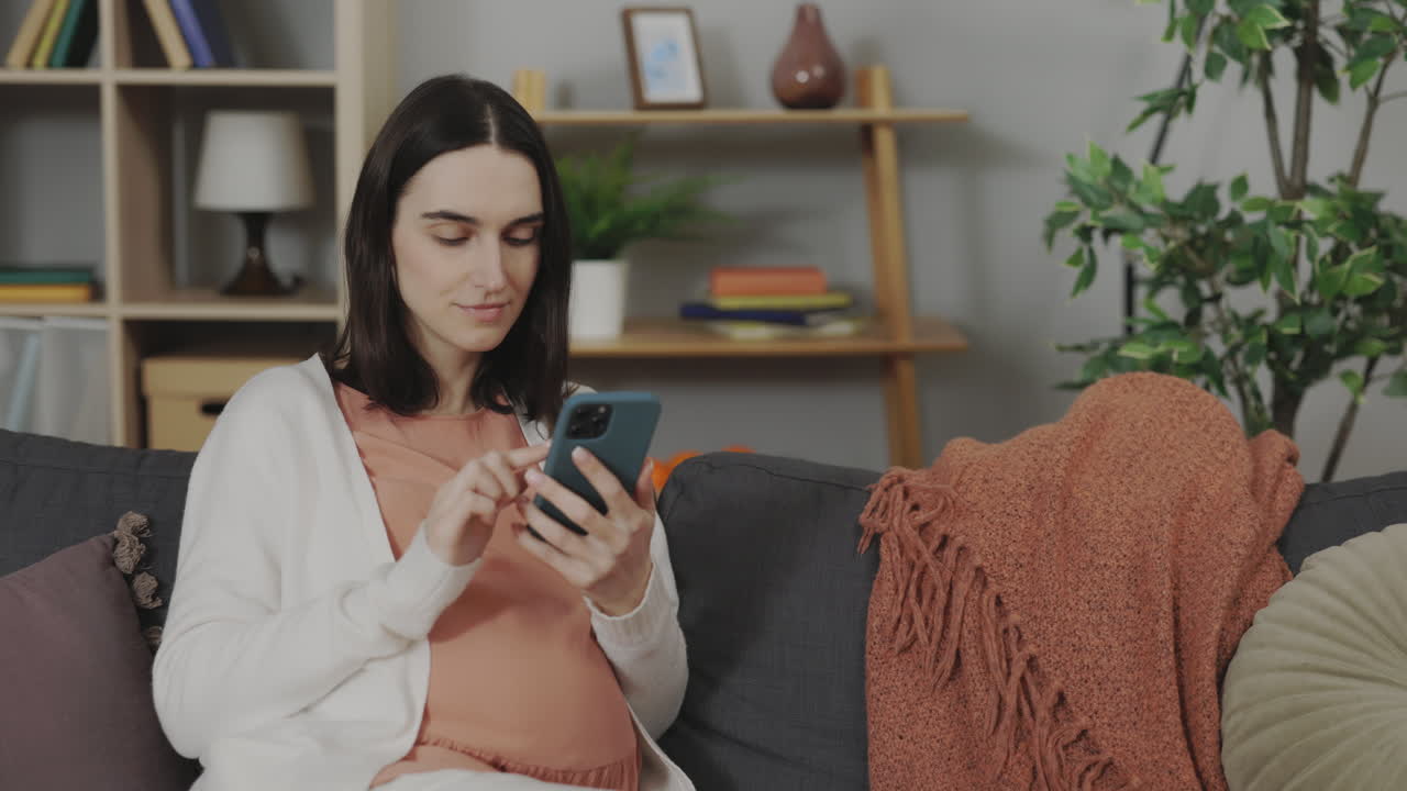 Pregnant woman using smartphone at home