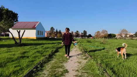 Wide-Shot-from-behind-woman-stroll-with-dog-on-leash