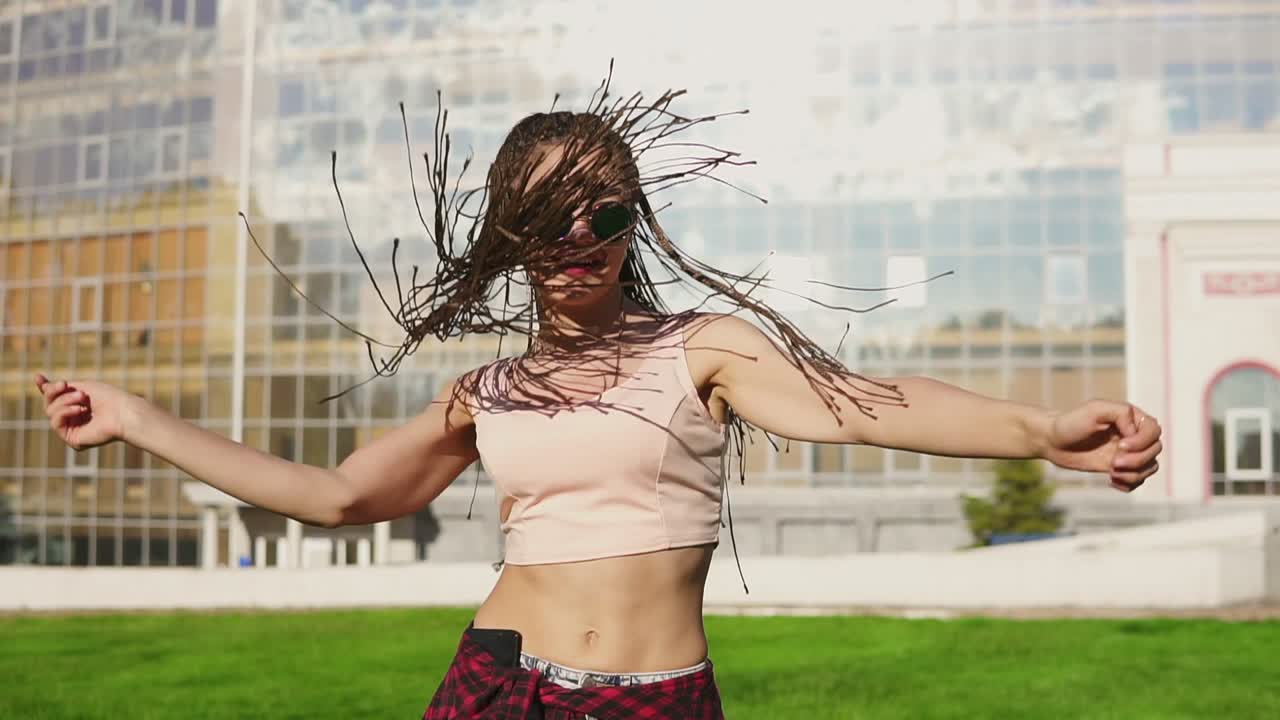 una mujer hermosa con vaqueros y gafas de sol escuchando música y bailando.