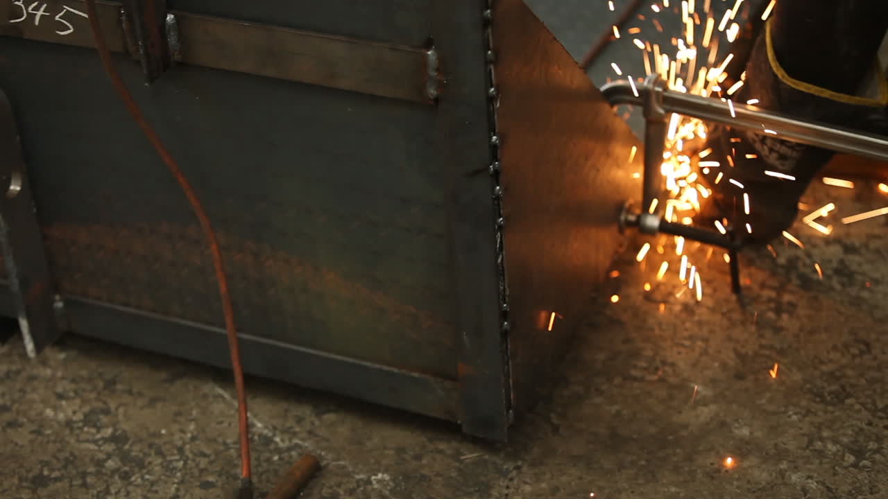 Saldatore che usa un morsetto per tenere insieme lamiere metalliche mentre lavora a un prodotto per un cliente