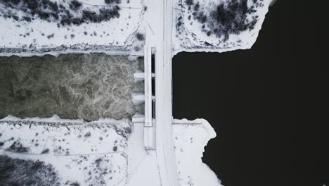 slow establishing shot aerial drone view rushing water notigi hydro dam river lake snowy landscape northern winter manitoba canada