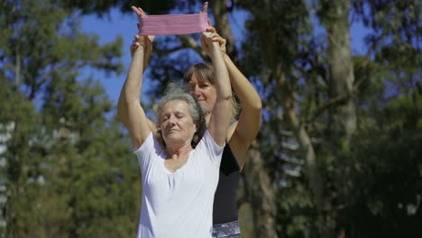 Focused-elderly-lady-with-personal-trainer-in-summer-park.