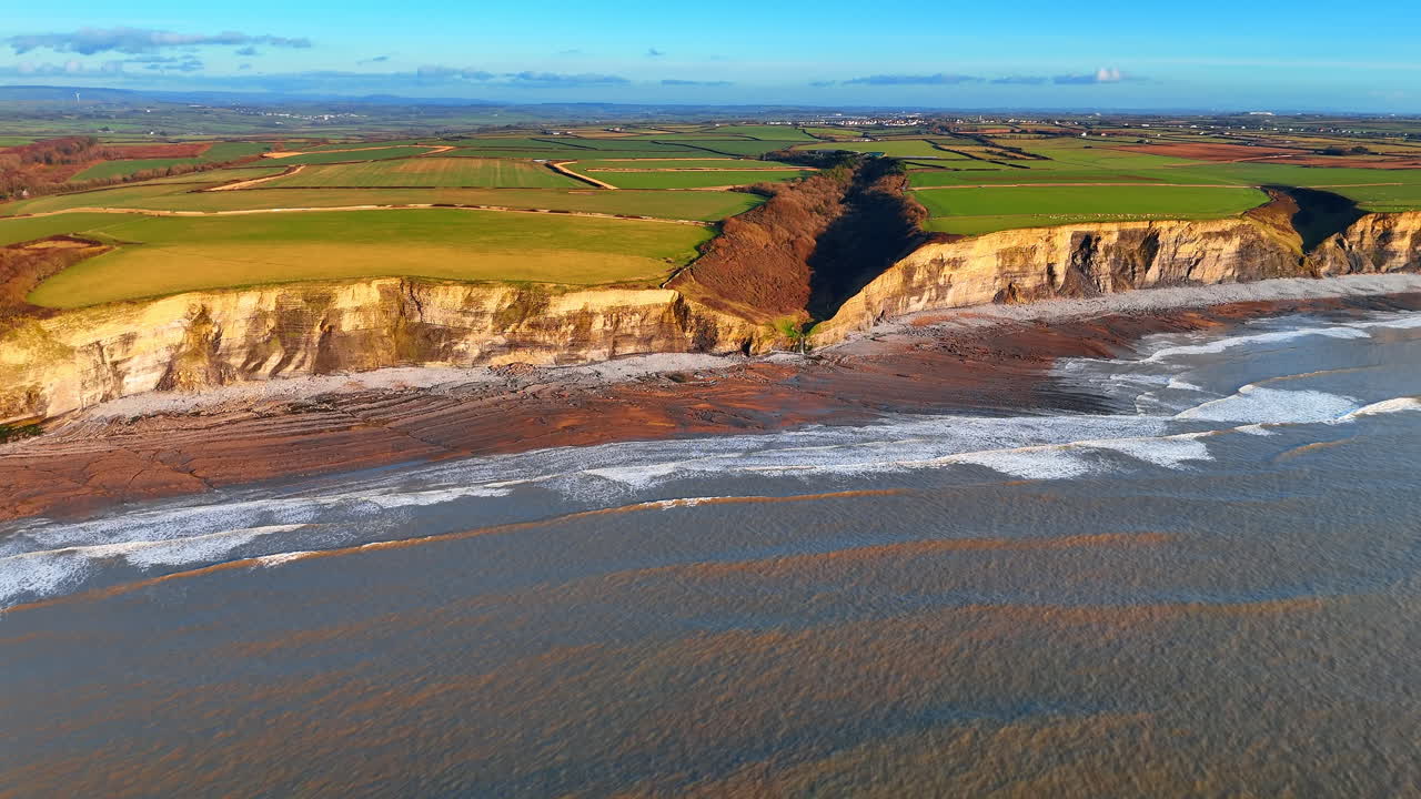 Costa con scogliere calcaree e piccola valle a Southerndown. Ripresa aerea della parete della scogliera e di una valle costiera che conduce alla spiaggia rocciosa di Dunraven Bay, Galles del Sud
