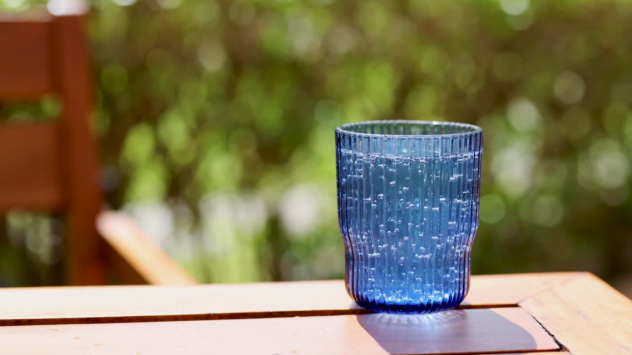 빛 아래 야외에서 반이는 물 거품이 있는 파란 유리