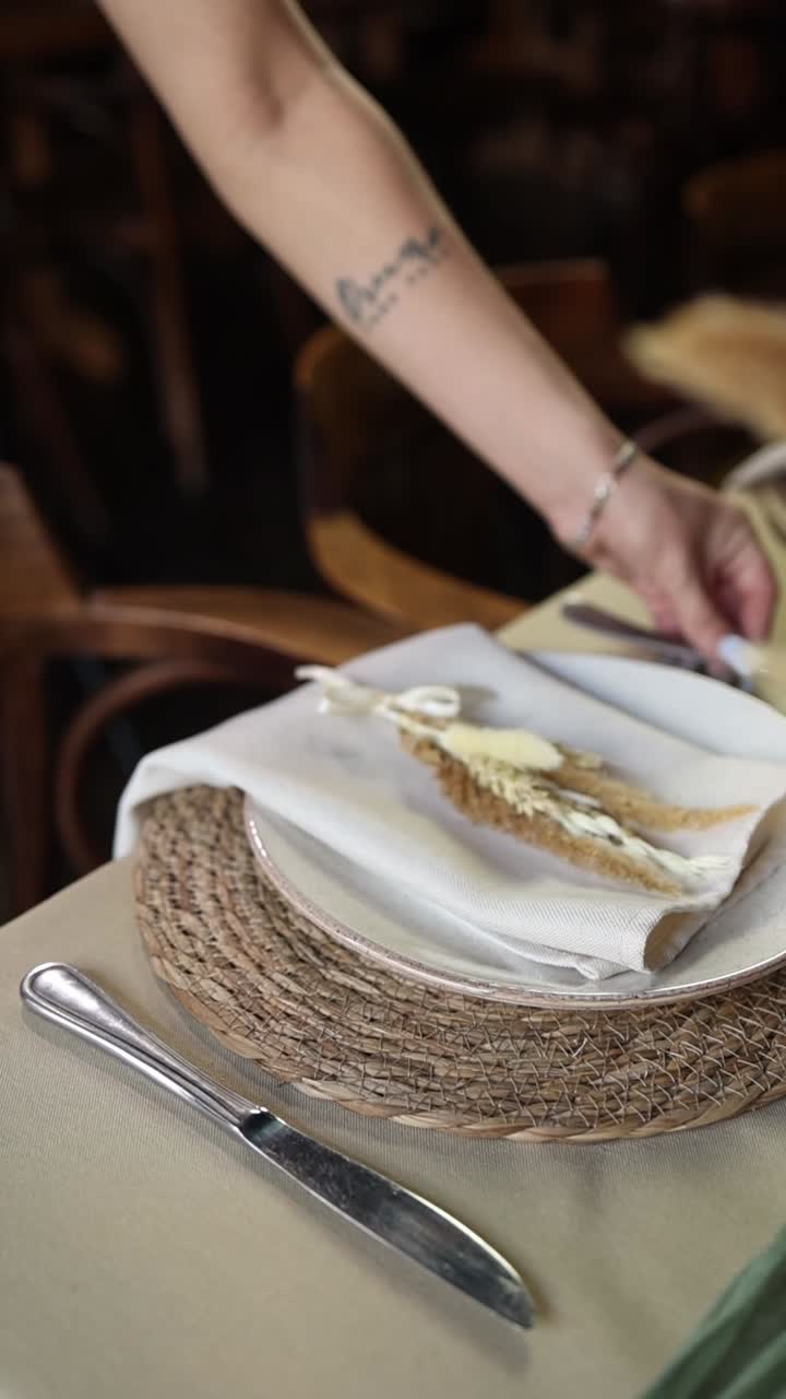 Persona poniendo una mesa con cubiertos elegantes y decoración rústica