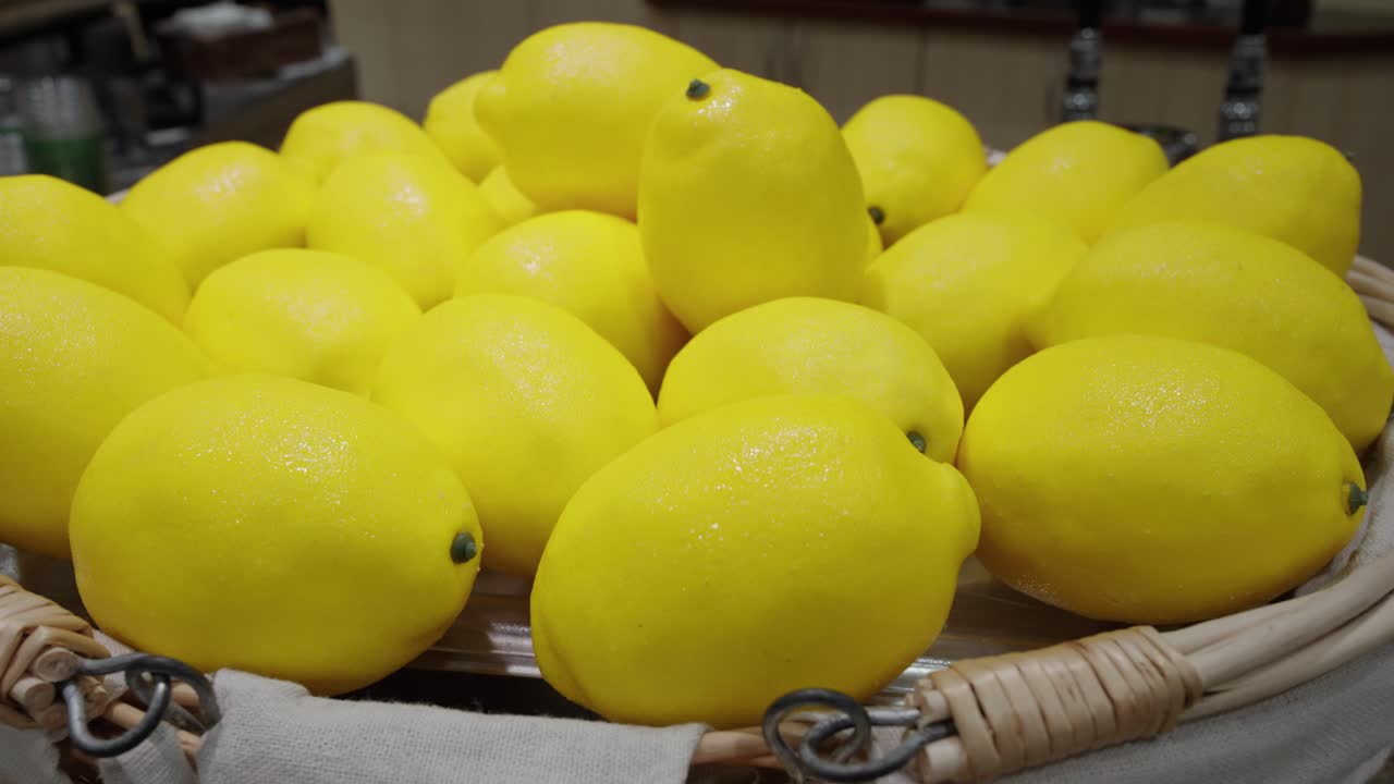 Bright yellow lemons in a bowl on display, glistening with condensation