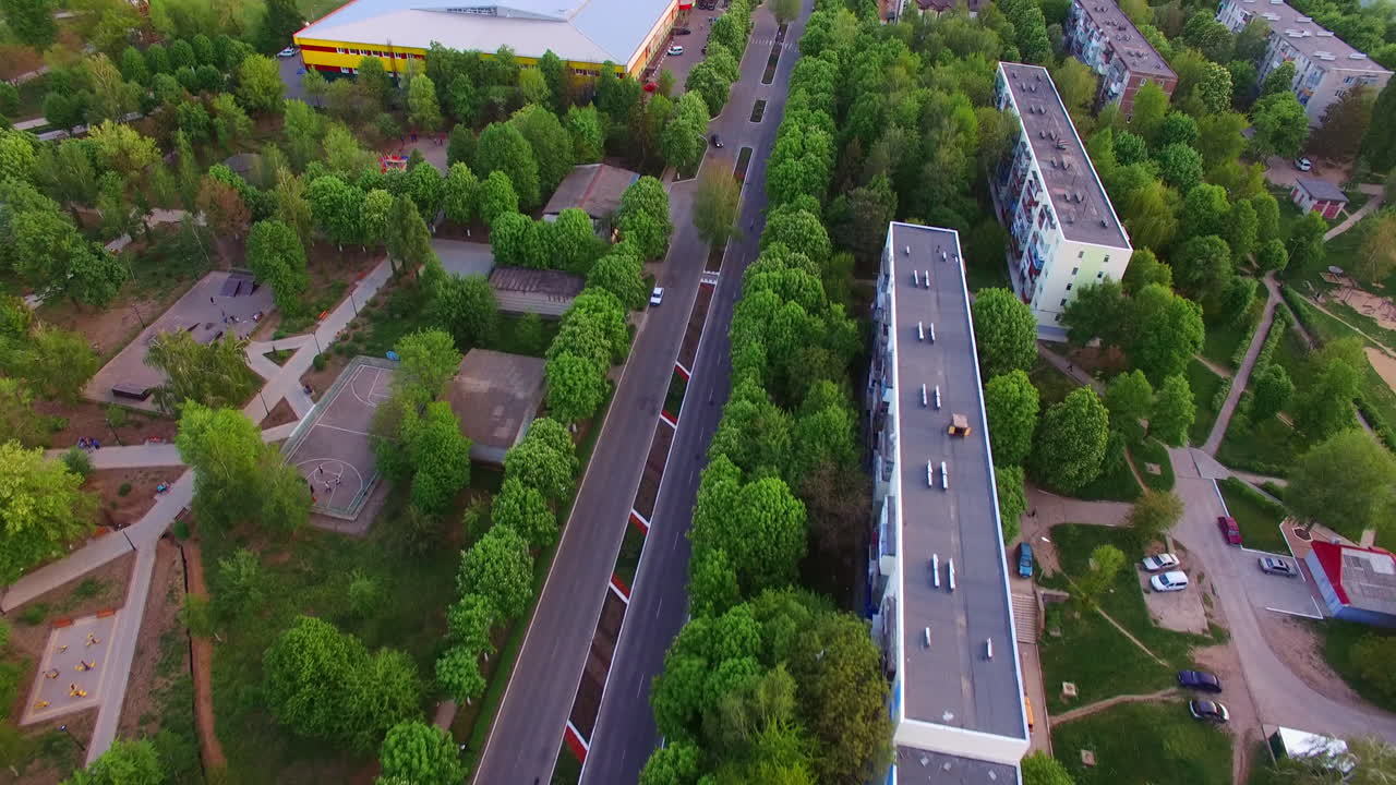 Good plain road going through the green residential area. Ukrainian city scenic panorama at the backdrop of blue sky.