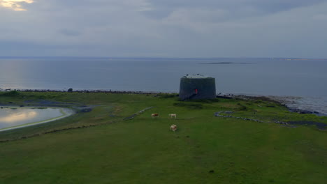 establishing aerial shot of aughinish martello tower on a peaceful twilight. county clare