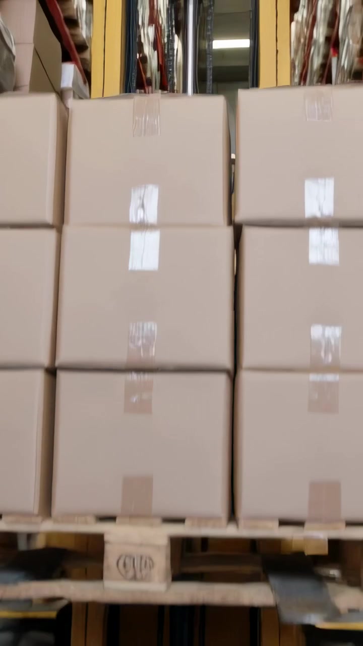 Vertical video: Driving forklift driver lifting pallet to rack in storage aisle, wearing vest