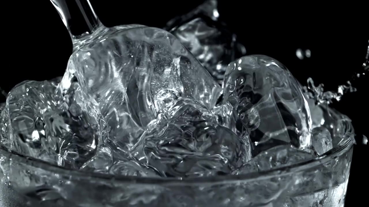 Acqua versata al rallentatore su cubetti di ghiaccio in un bicchiere