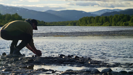 person drinks clean fresh water from freshwater lake in lapland, scandinavia, northern europe, medium wide shot