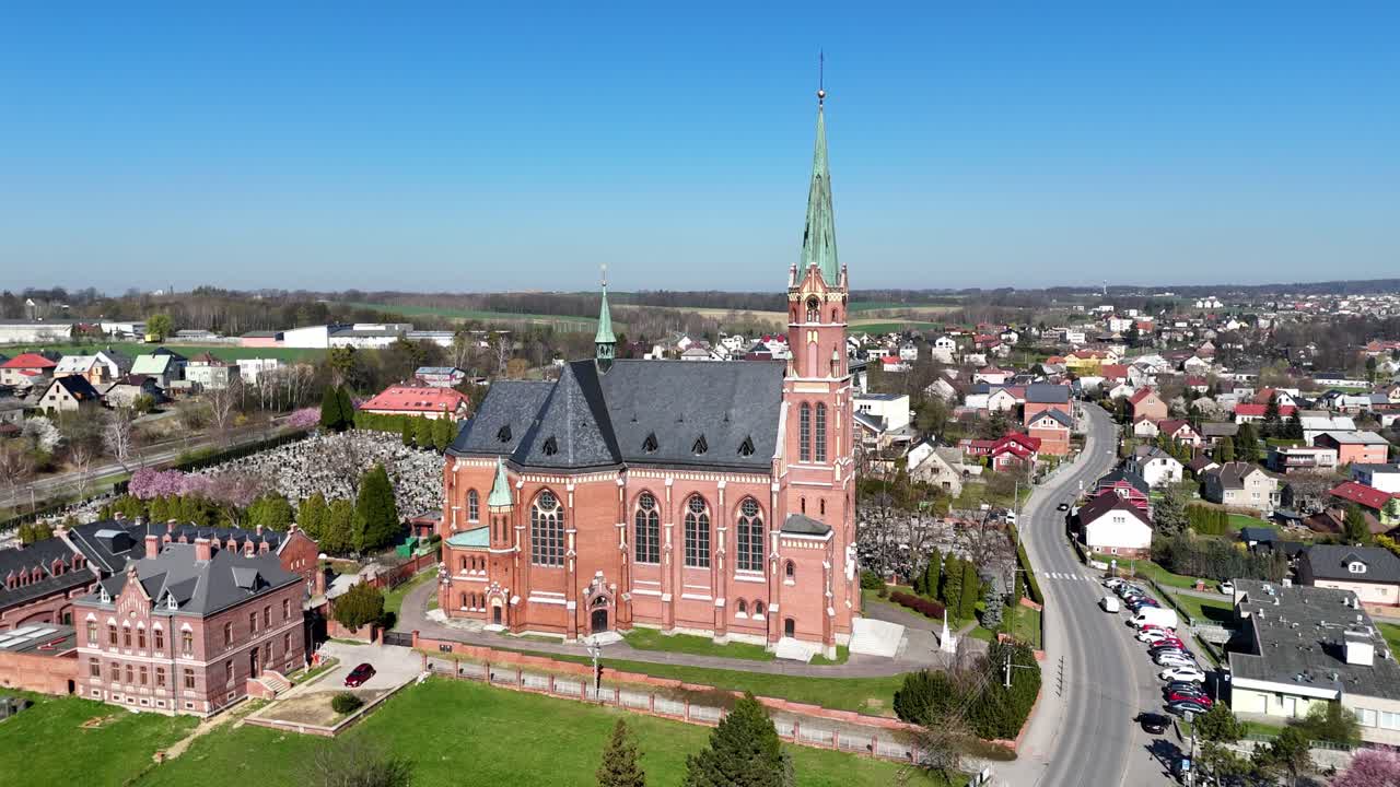 Drone cirkler om den rødspirede Sankt Mikuláš Kirke, der viser vertikal symmetri og detaljer ved middagstid.