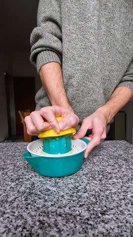 Man-squeezing-an-orange-on-a-juicer-at-his-home-kitchen