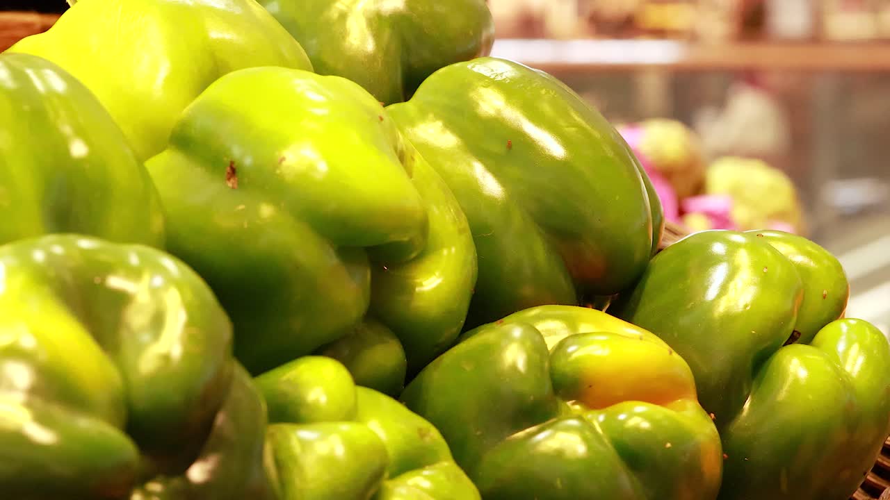 Vibrant green and red bell peppers arranged in a supermarket setting under warm lighting, showcasing fresh produce