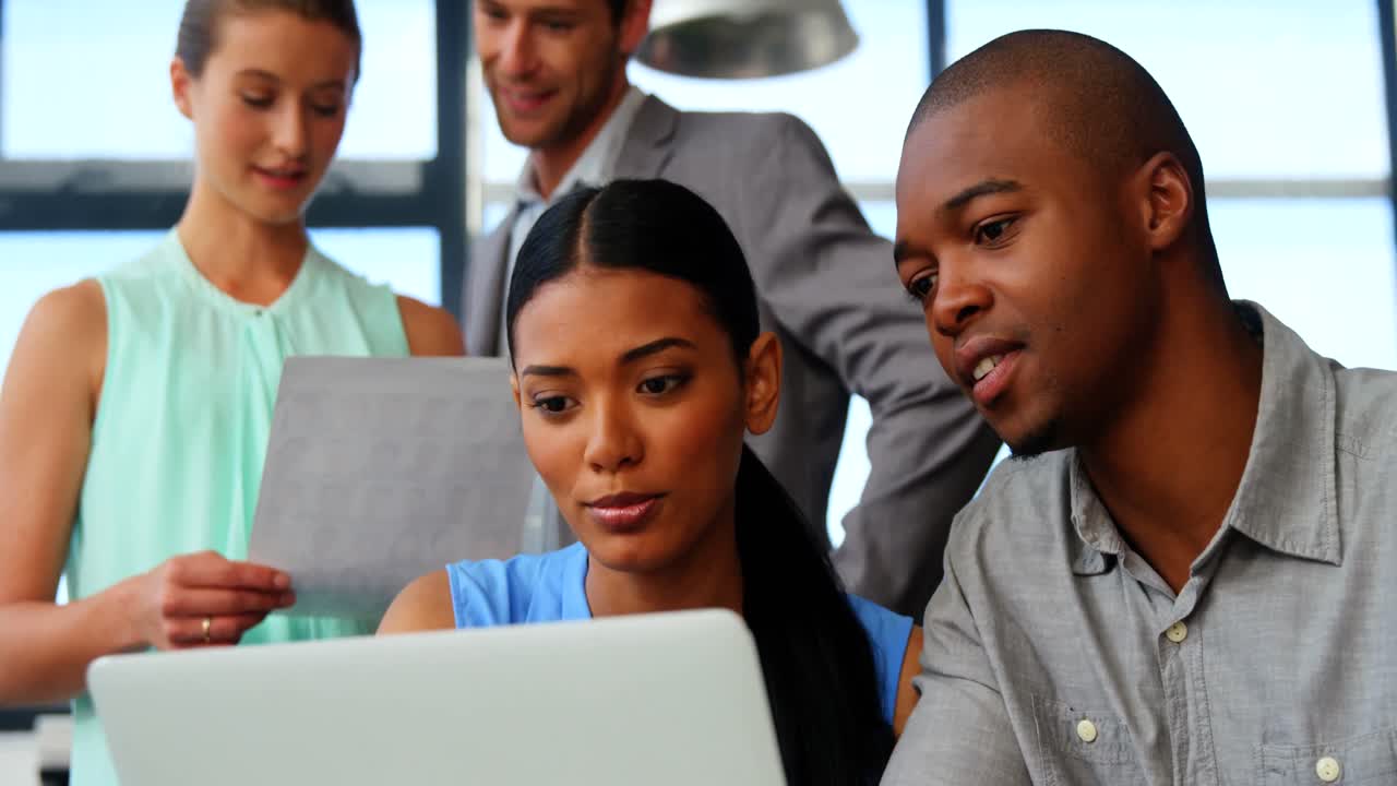 Business executives discussing over laptop