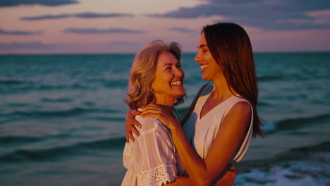 mother and daughter hugging on the beach at sunset