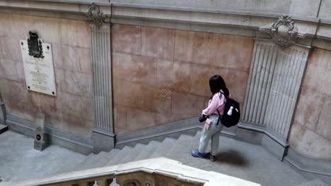 slow motion wide high angle shot of woman walking down stairs in palacio da bolsa in porto