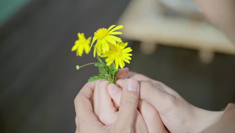Close-up,-man-hold-girl's-hand-with-the-yellow-daisy