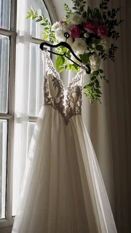 elegant wedding dress hanging by a window