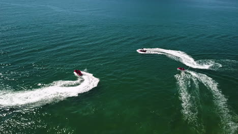 Tiro-Orbital-De-Tres-Motos-De-Agua-Rodando-En-Un-Mar-Azul-Y-Verde