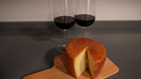 queso entero con un corte y dos vasos de vino tinto para la noche de la cita del día de san valentín