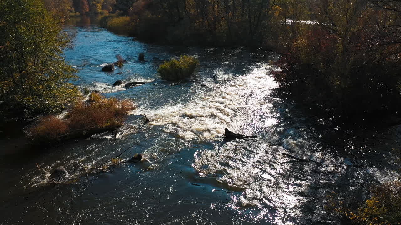 Un ampio fiume scorre al tramonto in autunno. I raggi del sole si riflettono nell'acqua del lago. Vista aerea