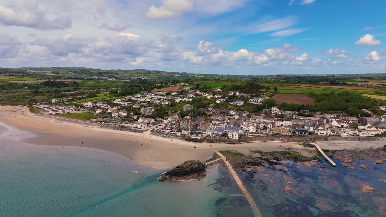 4K-Drohnenluftaufnahmen, die sich den Ufern von Marazion an der Mount's Bay nähern und Cornwalls malerische Küste, den Küstencharme und atemberaubende Ausblicke auf das Meer einfangen.