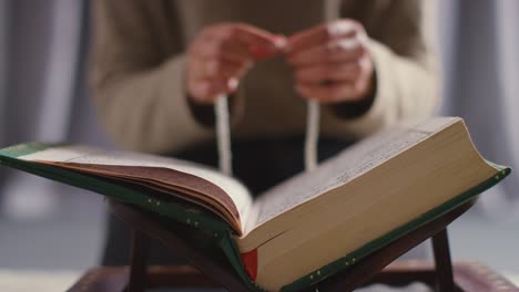 Close-Up-Of-Muslim-Woman-Praying-With-Prayer-Beads-Over-Open-Copy-Of-The-Quran-At-Home-1