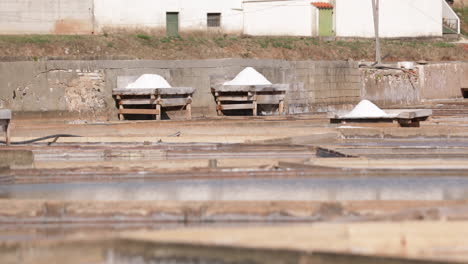 Holzdecks-Mit-Salzhaufen,-Die-Bei-Sonnigem-Wetter-In-Salinas-De-Rio-Maior-In-Portugal-Trocknen