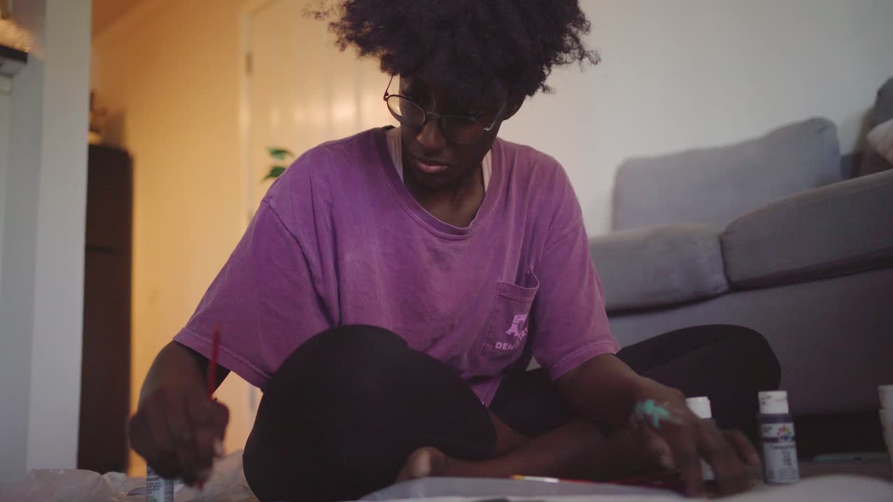 Young African woman drawing picture at home
