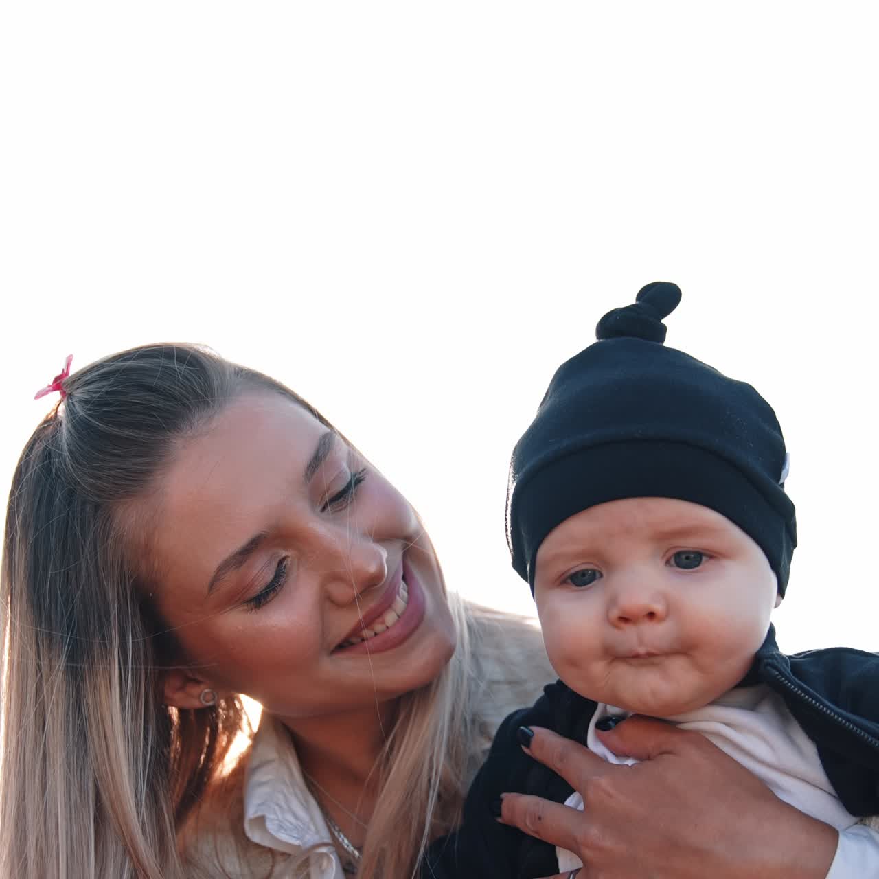 Beautiful Caucasian mother smiles to her child she's holding. Cute baby boy is focused on camera. Vertical view