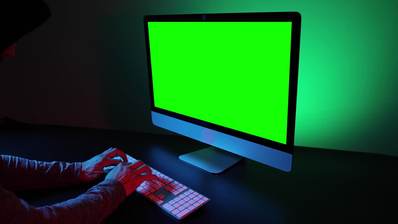 manos escribiendo en un teclado y pantalla verde.