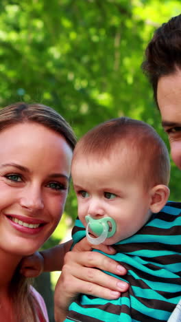 pais orgulhosos sorrindo para a câmera segurando o filho bebê