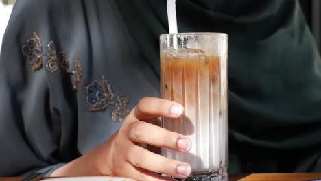 una mujer bebiendo café helado.