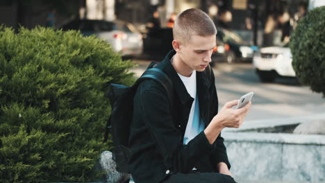 joven estudiante usando el teléfono móvil al aire libre.