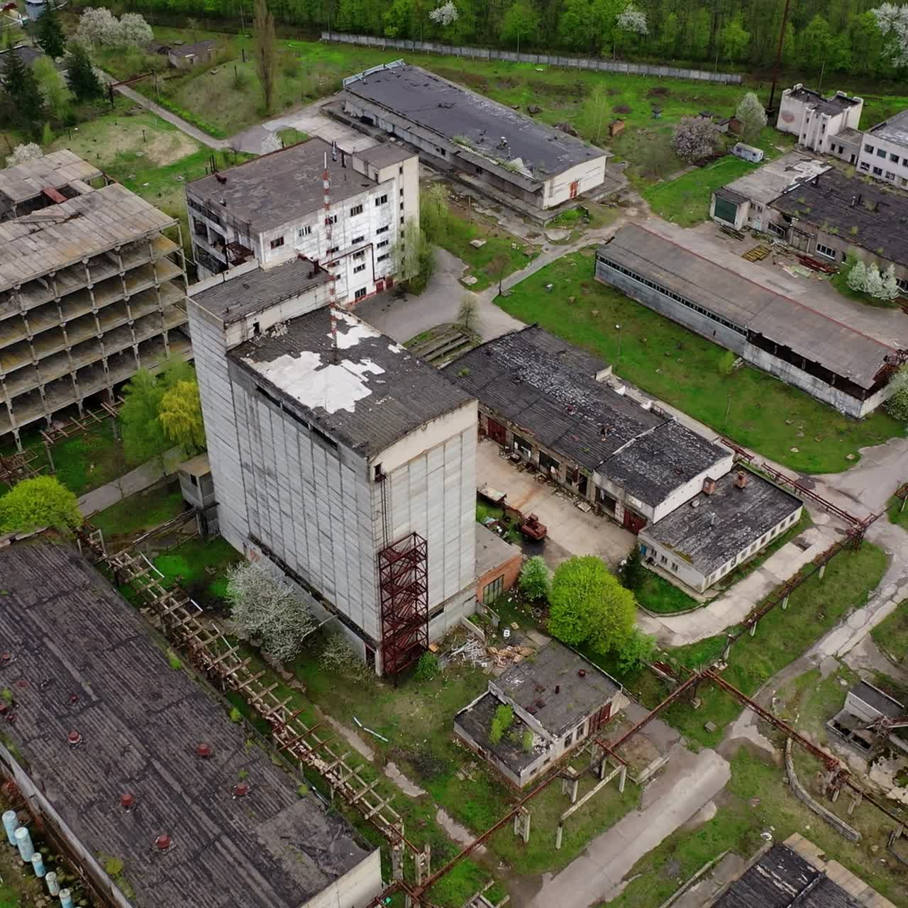 Large territory of abandoned plant. Damaged buildings of an old factory. Ruined industry in springtime. Aerial view