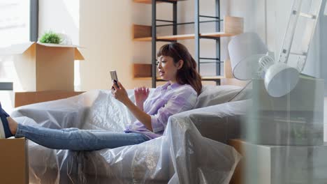 Mujer-Con-Teléfono-Haciendo-Una-Videollamada-En-Su-Nueva-Casa.-Concepto-De-Mudanza,-Personas-Y-Bienes-Raíces.-Mujer-Asiática-Feliz-Y-Sonriente-Con-Teléfono-Inteligente-Y-Cajas-Haciendo-Una-Videollamada-En-Su-Nueva-Casa.