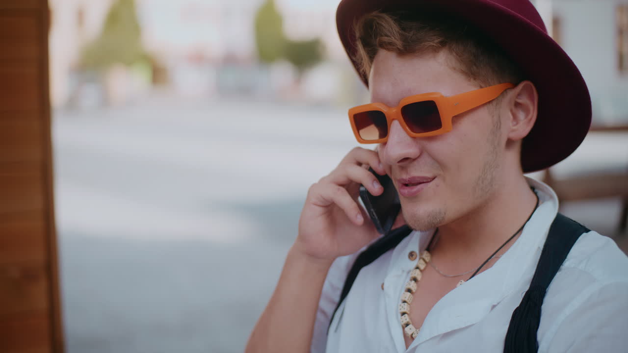 молодой человек разговаривает по телефону на открытом воздухе