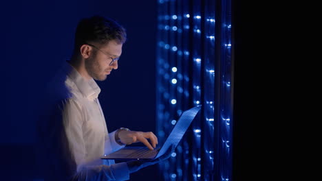 data center it specialists coworking in secure server room of cyberspace. male administrator pointing at error server cabinet running diagnostics on laptop computer