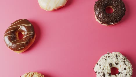 video of donuts with icing on pink background