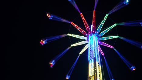 4k tall illuminated merry-go-round rotating at amusement park on background of black night sky